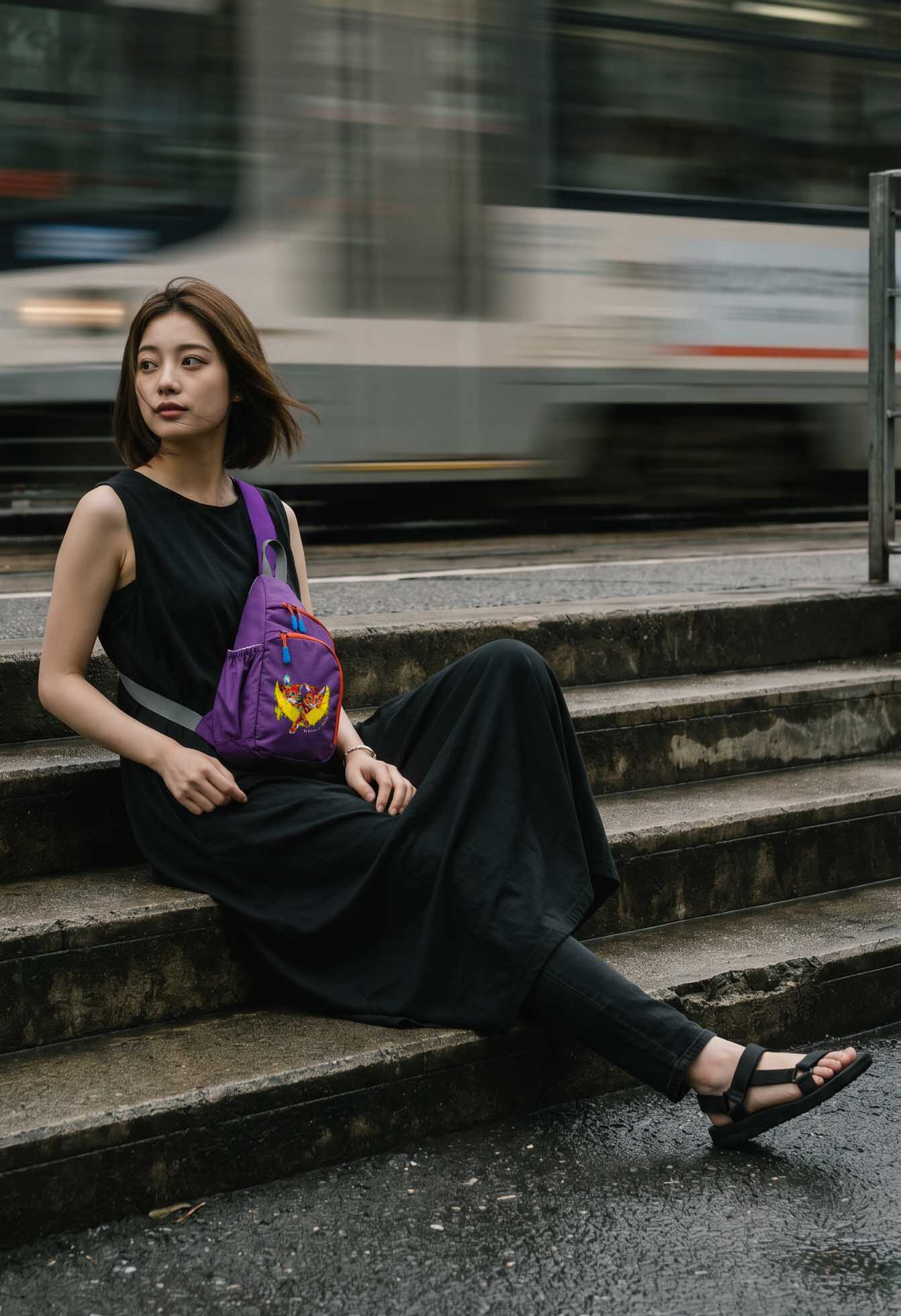 街の階段に腰かける女性・パープルのNEKONI SLINGバッグ